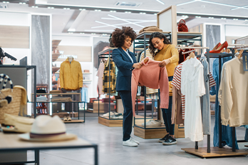 Twee mensen kijken naar een trui in een kledingwinkel