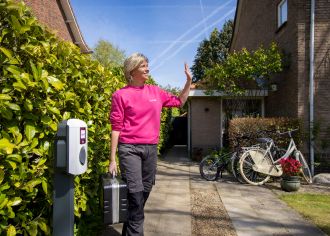 Medewerker van Essent staat naast laadpaal op een oprit.