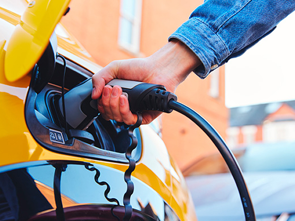 Persoon stopt een laadkabel in een gele auto 