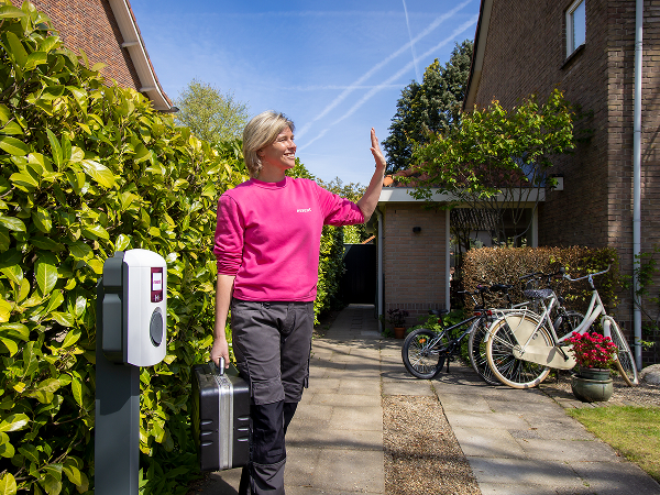 Essent medewerker staat naast laadpaal en zwaait 
