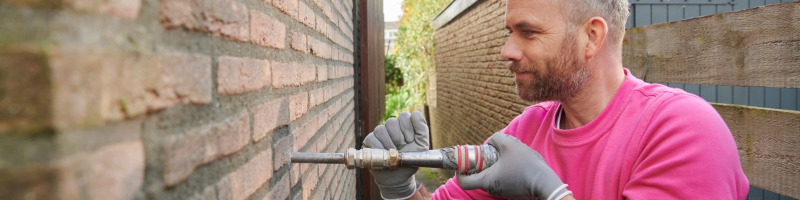 man isoleert buitenkant garagemuur