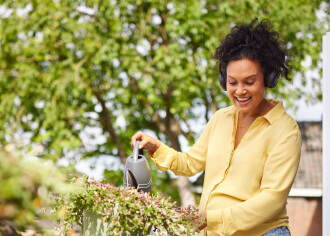 vrouw watert plant met gieter op balkon