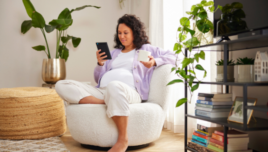 Zwangere vrouw met kopje en e-reader