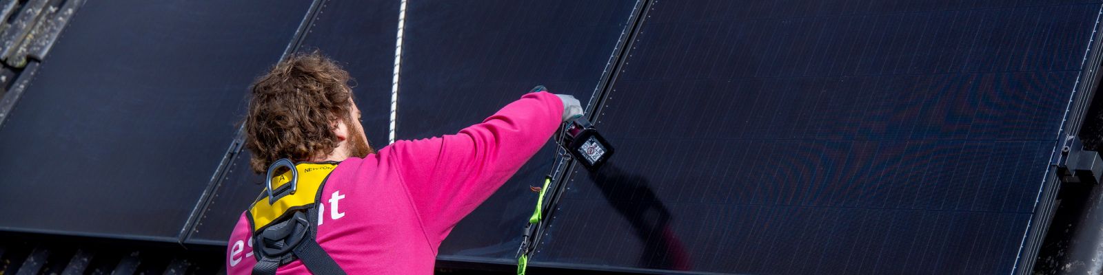 man legt zwarte zonnepanelen