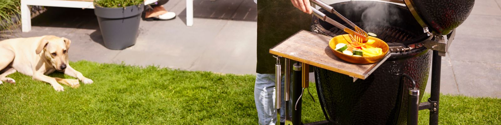 man barbecuet in de tuin