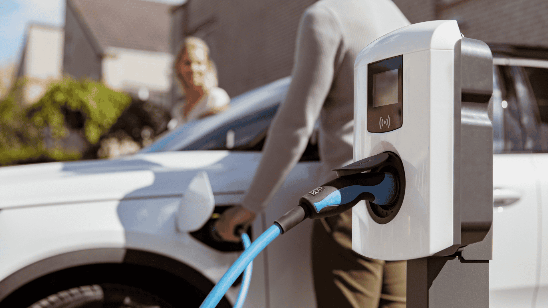 Man laadt elektrische auto op bij laadpaal.