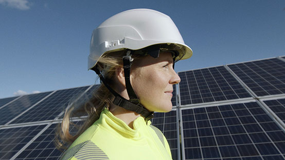 Vrouw met bouwhelm op en zonnepanelen op de achtergrond