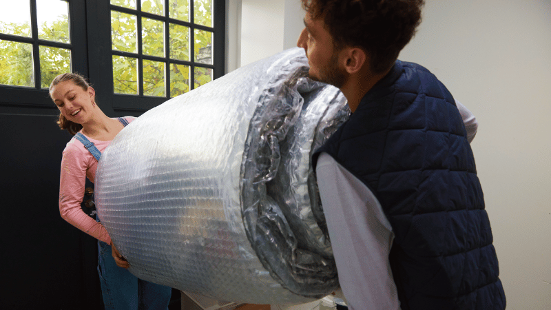 Twee mensen dragen samen een rol met isolatiemateriaal