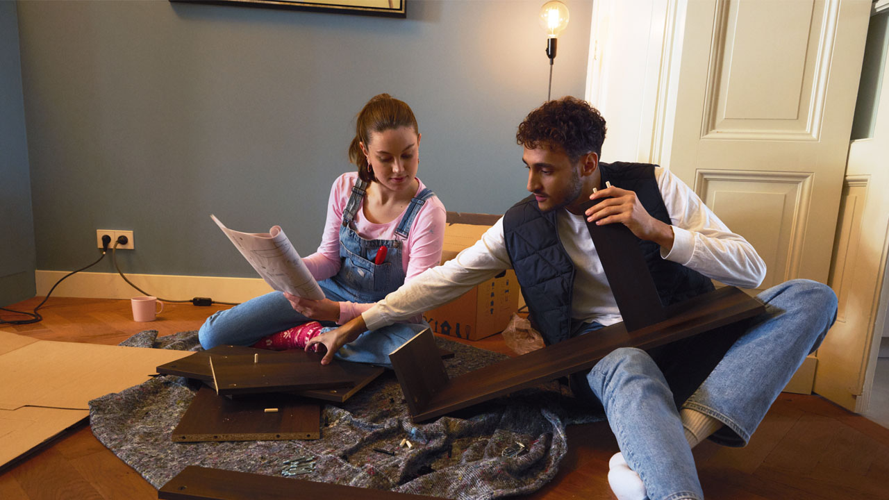 Twee mensen zetten een meubel in elkaar en lezen de instructie