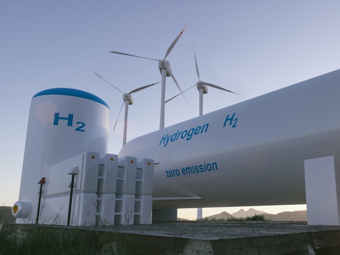 Een windmolen staat naast een installatie voor waterstofopslag in een open landschap.