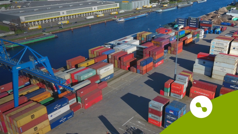 Een containeroverslag naast een kanaal"