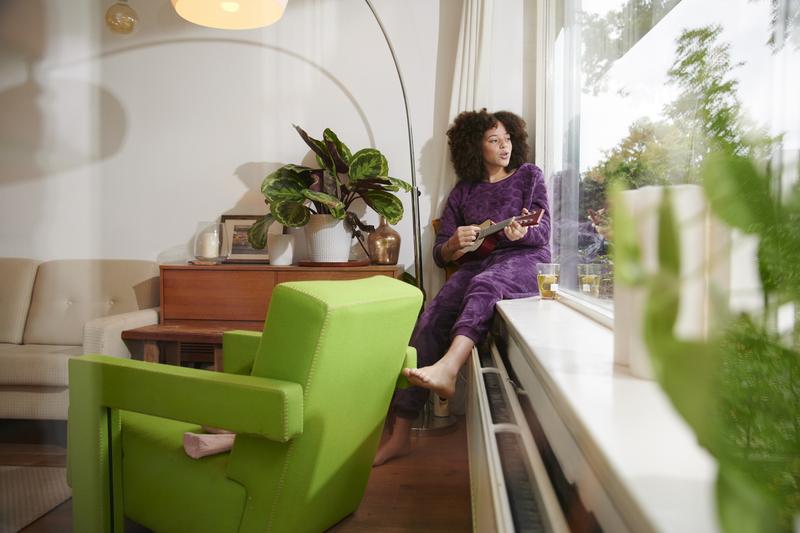 Essent Gas, dame zit op vensterbank op warme radiator naar buiten te kijken